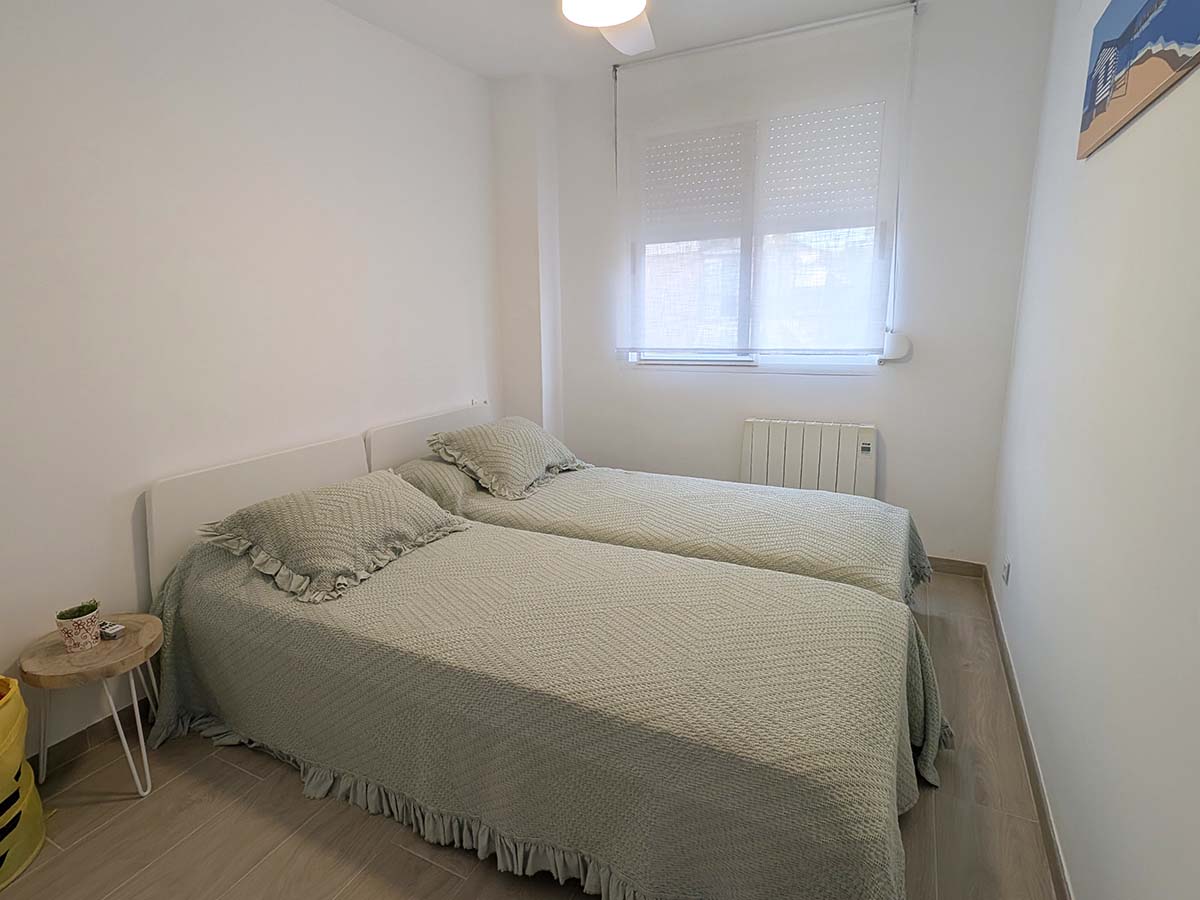 Slaapkamer met tweepersoonsbed en plafondventilator